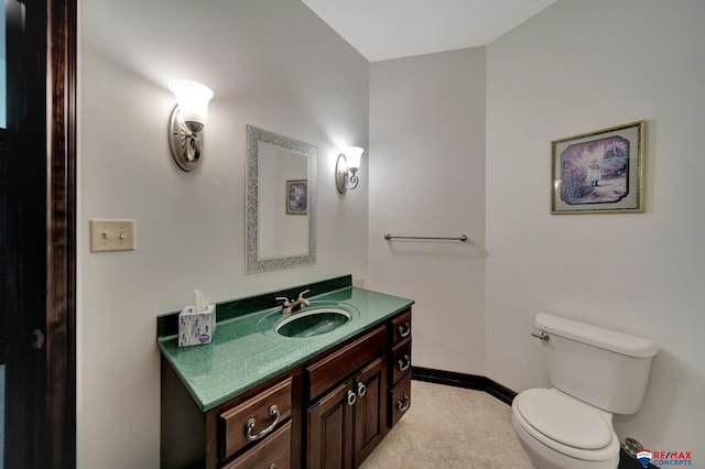 half bathroom featuring toilet, vanity, and baseboards