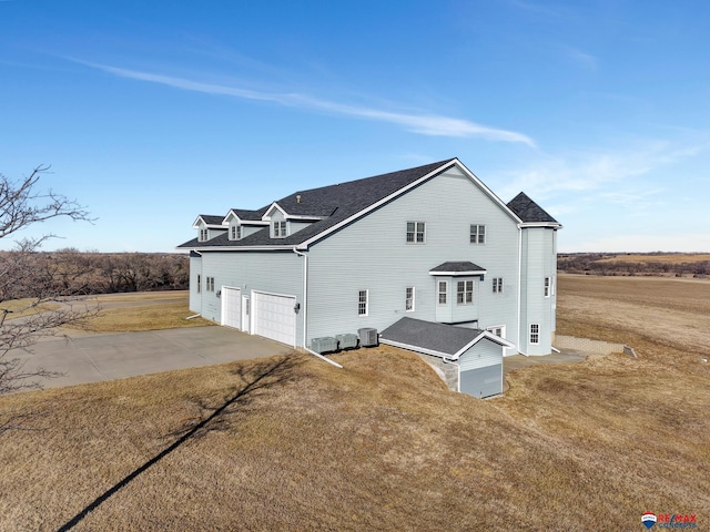 view of home's exterior featuring central air condition unit, roof with shingles, driveway, and a lawn