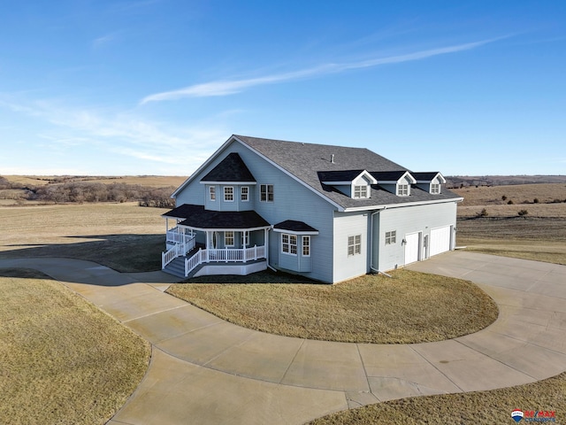 shingle-style home featuring driveway, a garage, a shingled roof, a porch, and a front lawn