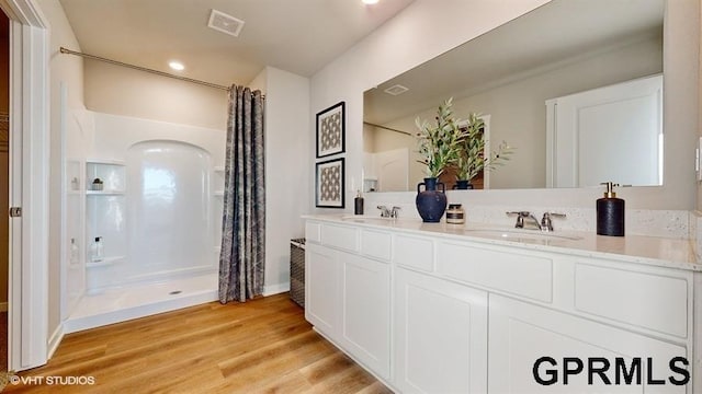 bathroom with wood-type flooring, vanity, and walk in shower