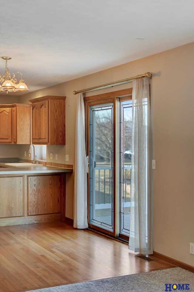 kitchen featuring an inviting chandelier, sink, hanging light fixtures, and light hardwood / wood-style flooring