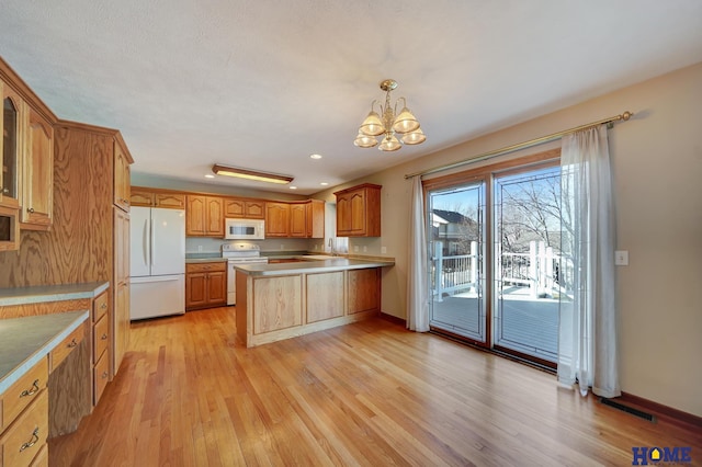 kitchen featuring sink, a chandelier, hanging light fixtures, white appliances, and light hardwood / wood-style flooring