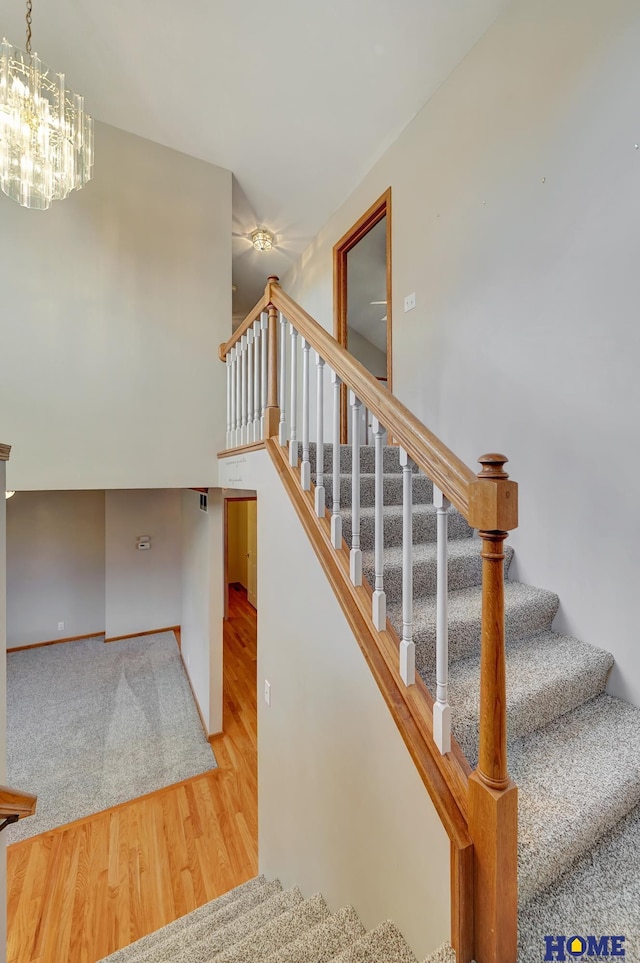 staircase featuring hardwood / wood-style floors and an inviting chandelier