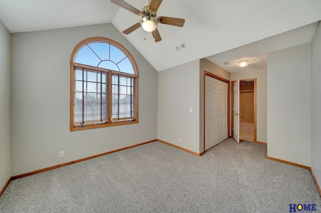 spare room featuring light carpet, vaulted ceiling, and ceiling fan