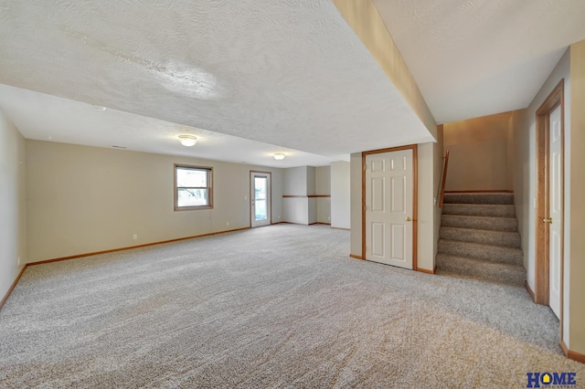 basement featuring light colored carpet and a textured ceiling