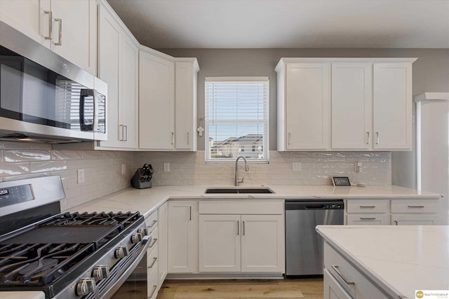 kitchen featuring white cabinetry, appliances with stainless steel finishes, light stone countertops, and sink