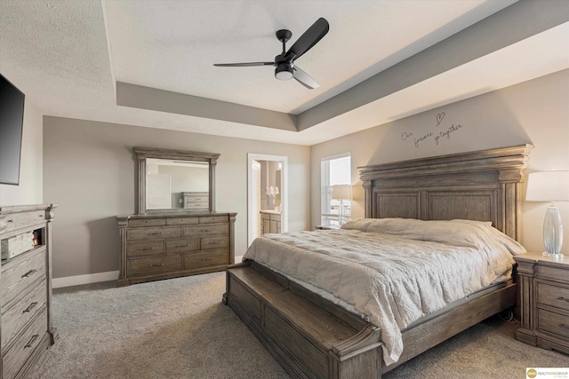 carpeted bedroom featuring ceiling fan, a tray ceiling, a textured ceiling, and ensuite bathroom