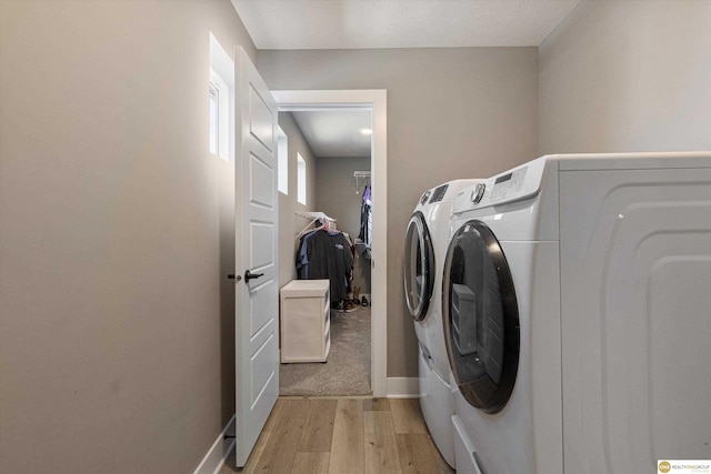 clothes washing area featuring washer and clothes dryer and light hardwood / wood-style floors