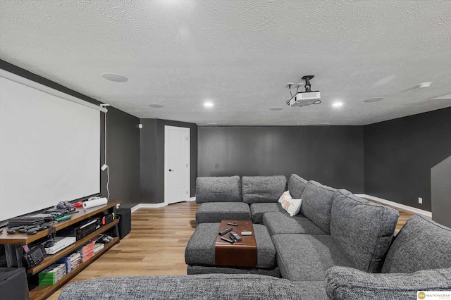 cinema room with light hardwood / wood-style floors and a textured ceiling