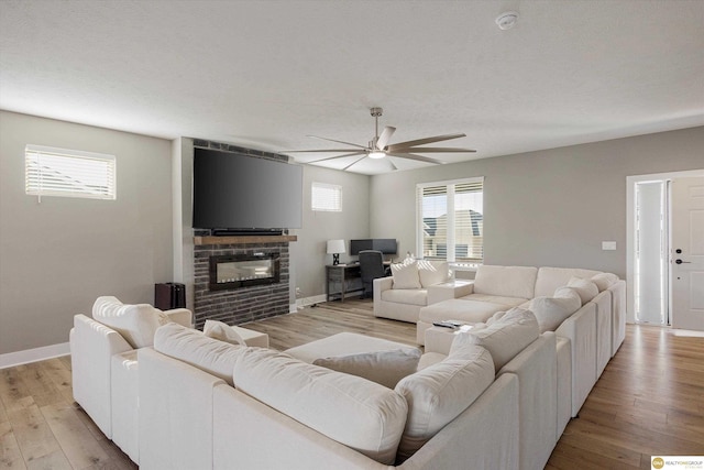 living room with a brick fireplace, light hardwood / wood-style flooring, and ceiling fan