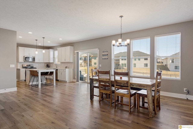 dining area with dark wood-type flooring, plenty of natural light, and a notable chandelier