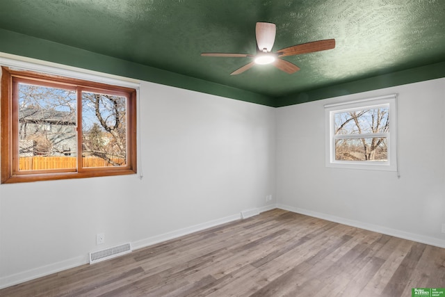 unfurnished room with ceiling fan, light hardwood / wood-style flooring, and a textured ceiling