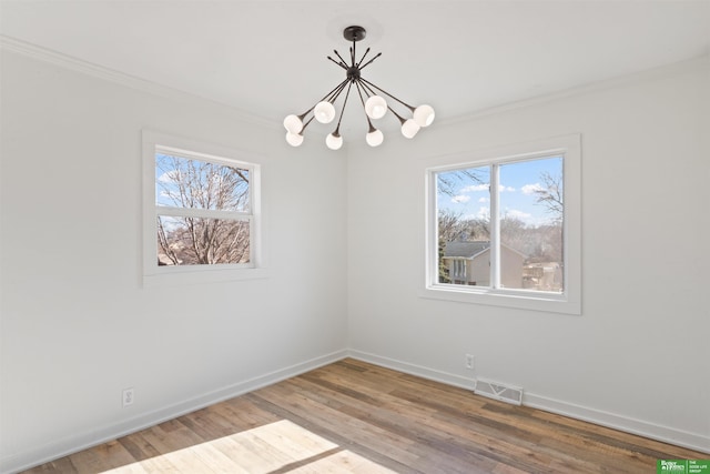 unfurnished room featuring a notable chandelier, wood-type flooring, and ornamental molding