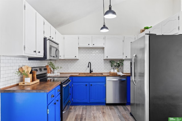 kitchen with blue cabinetry, wood counters, sink, hanging light fixtures, and stainless steel appliances