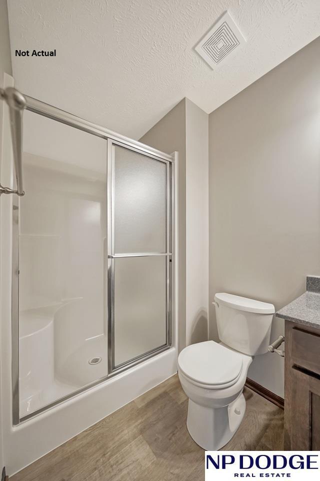 bathroom featuring hardwood / wood-style flooring, vanity, a shower with shower door, and a textured ceiling