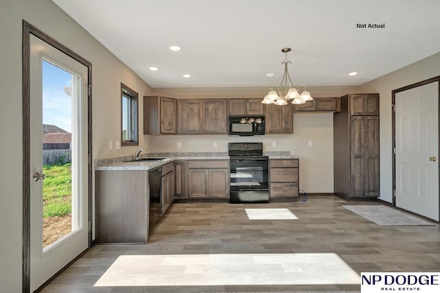 kitchen featuring sink, decorative light fixtures, light hardwood / wood-style flooring, a notable chandelier, and black appliances