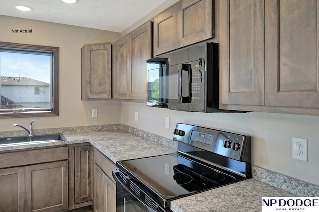 kitchen featuring sink, black appliances, and a textured ceiling