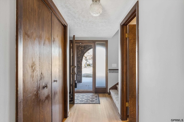 doorway featuring a textured ceiling and light wood-type flooring