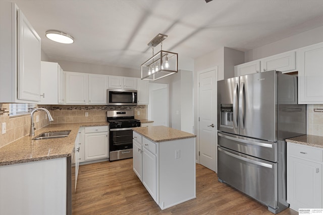 kitchen with pendant lighting, sink, stainless steel appliances, a center island, and white cabinets