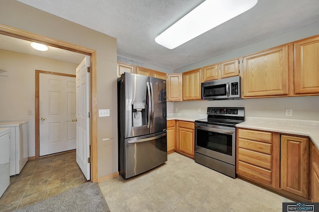 kitchen with stainless steel appliances, independent washer and dryer, and a textured ceiling