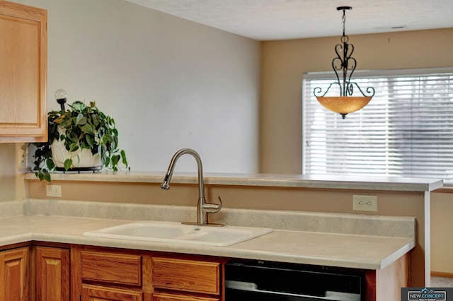 kitchen featuring a healthy amount of sunlight, black dishwasher, sink, and hanging light fixtures