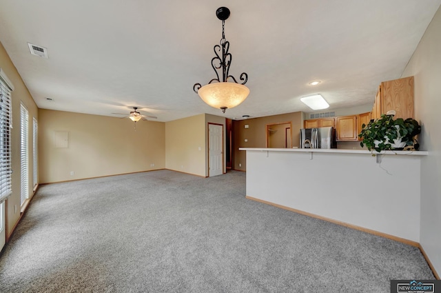 kitchen featuring ceiling fan, stainless steel fridge, kitchen peninsula, pendant lighting, and light colored carpet