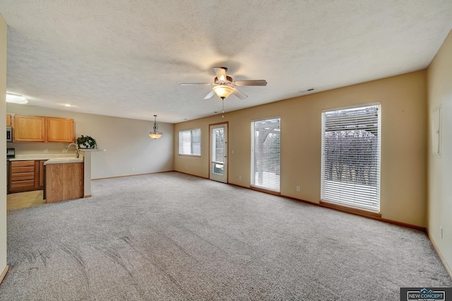 unfurnished living room with light colored carpet, a textured ceiling, and ceiling fan