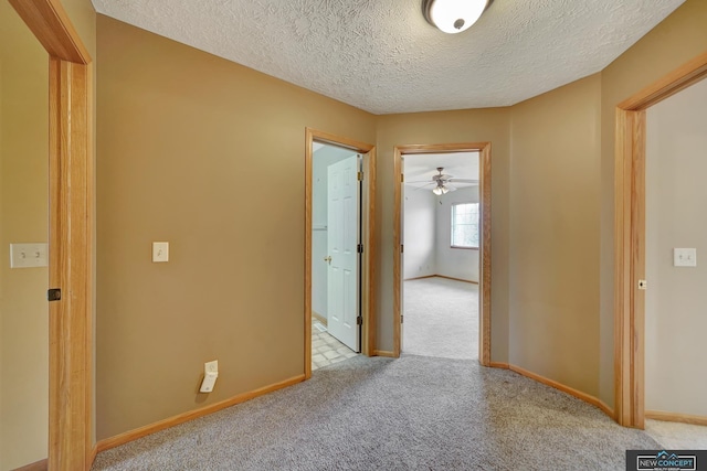 corridor with light carpet and a textured ceiling