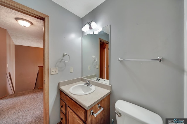 bathroom with vanity, toilet, and a textured ceiling