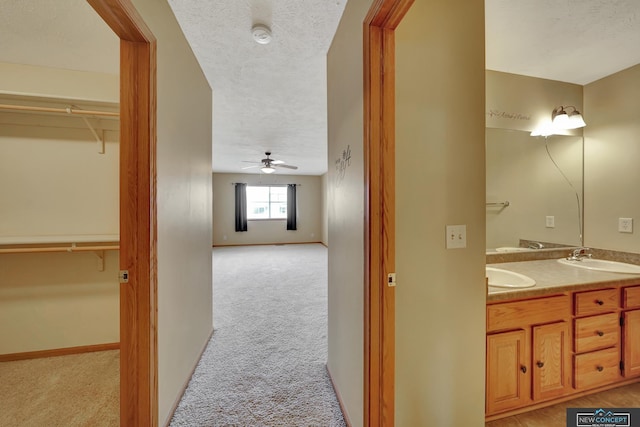 bathroom with ceiling fan, vanity, and a textured ceiling