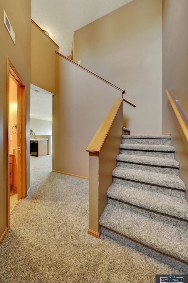 stairs featuring carpet and a high ceiling