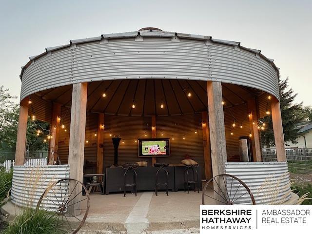 patio terrace at dusk featuring a gazebo and a bar