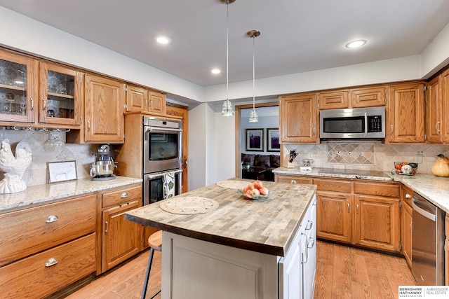 kitchen featuring pendant lighting, wooden counters, a center island, light hardwood / wood-style floors, and stainless steel appliances