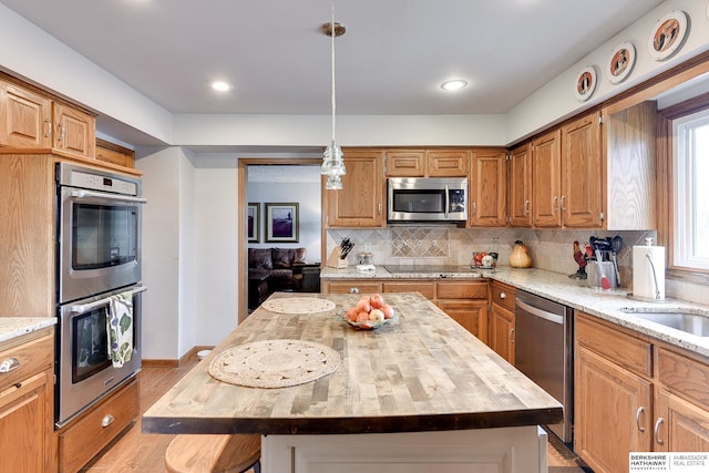 kitchen with appliances with stainless steel finishes, wooden counters, a center island, and decorative backsplash