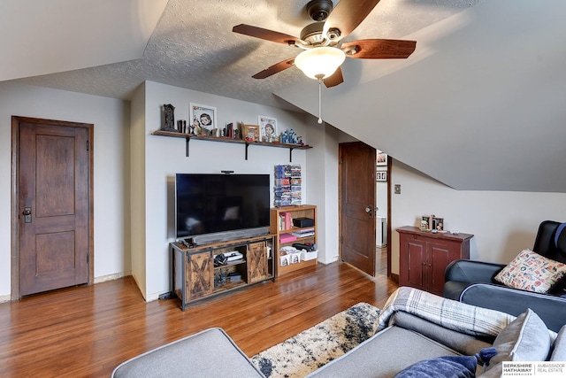 living room with hardwood / wood-style flooring, ceiling fan, lofted ceiling, and a textured ceiling