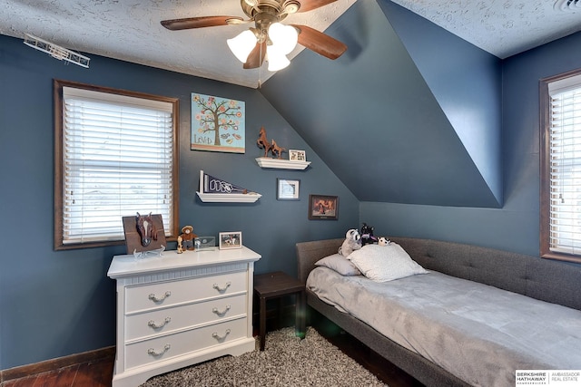 bedroom with ceiling fan, vaulted ceiling, and a textured ceiling