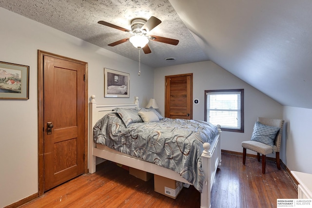 bedroom with ceiling fan, lofted ceiling, dark hardwood / wood-style floors, and a textured ceiling