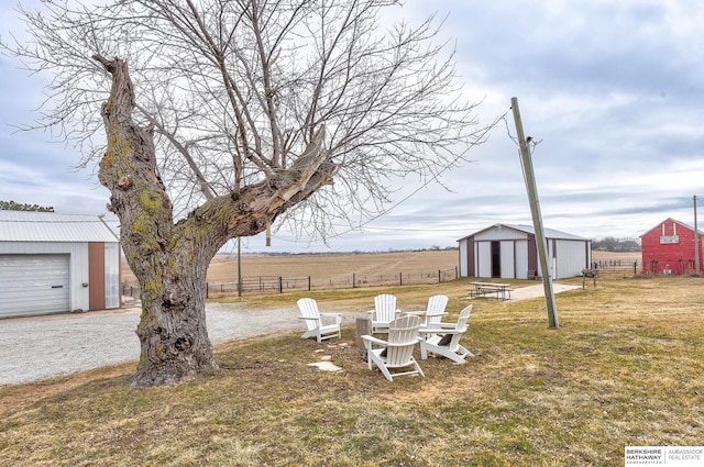 view of yard with an outbuilding, a garage, and a rural view