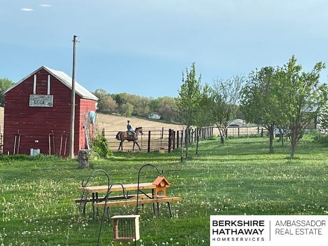 view of property's community with a rural view, an outbuilding, and a lawn