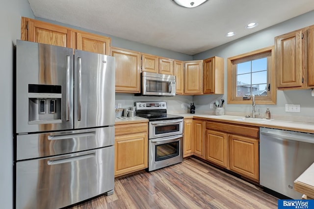 kitchen with hardwood / wood-style flooring, stainless steel appliances, sink, and a textured ceiling