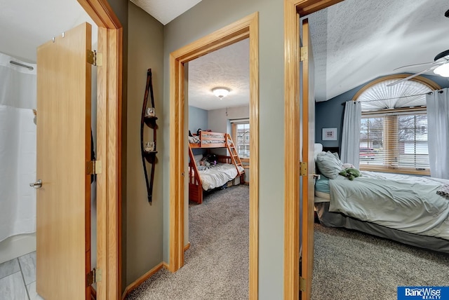 corridor with light colored carpet and a textured ceiling