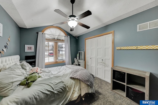 carpeted bedroom with ceiling fan, lofted ceiling, a closet, and a textured ceiling