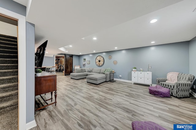 living room with a barn door and light hardwood / wood-style flooring