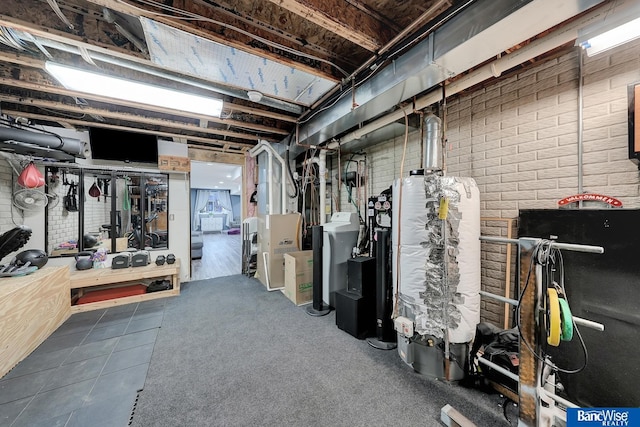 basement with brick wall, dark tile patterned flooring, and gas water heater