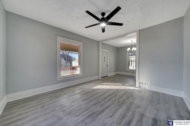 interior space featuring ceiling fan with notable chandelier, light wood-type flooring, a textured ceiling, and a wealth of natural light