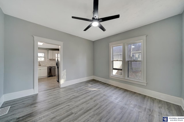 unfurnished room with sink, ceiling fan, and light wood-type flooring