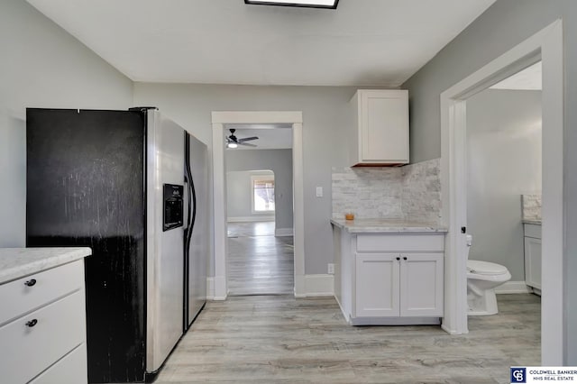 kitchen with tasteful backsplash, light wood-type flooring, white cabinets, and stainless steel refrigerator with ice dispenser