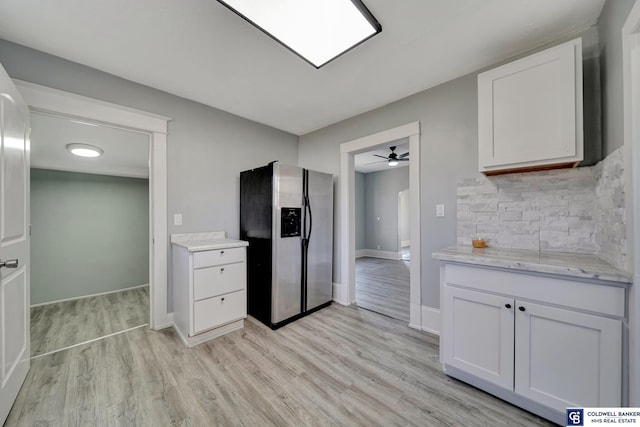 kitchen with white cabinetry, stainless steel fridge, decorative backsplash, light stone counters, and light wood-type flooring