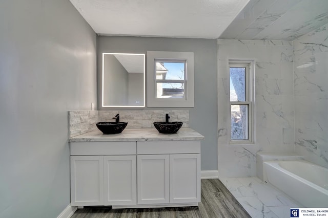 bathroom featuring tasteful backsplash, vanity, and a tub to relax in