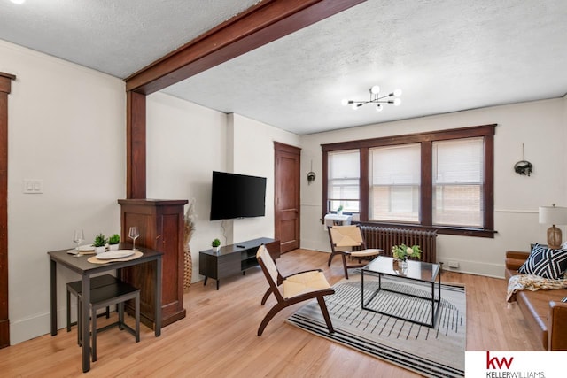 living room featuring radiator heating unit, light hardwood / wood-style floors, and a textured ceiling